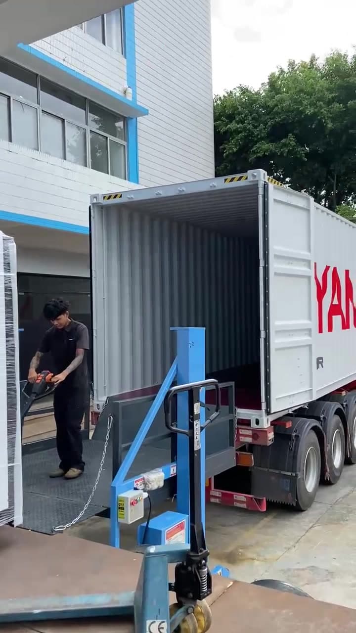 Operario cargando una máquina embalada en un camión con zorra hidráulica