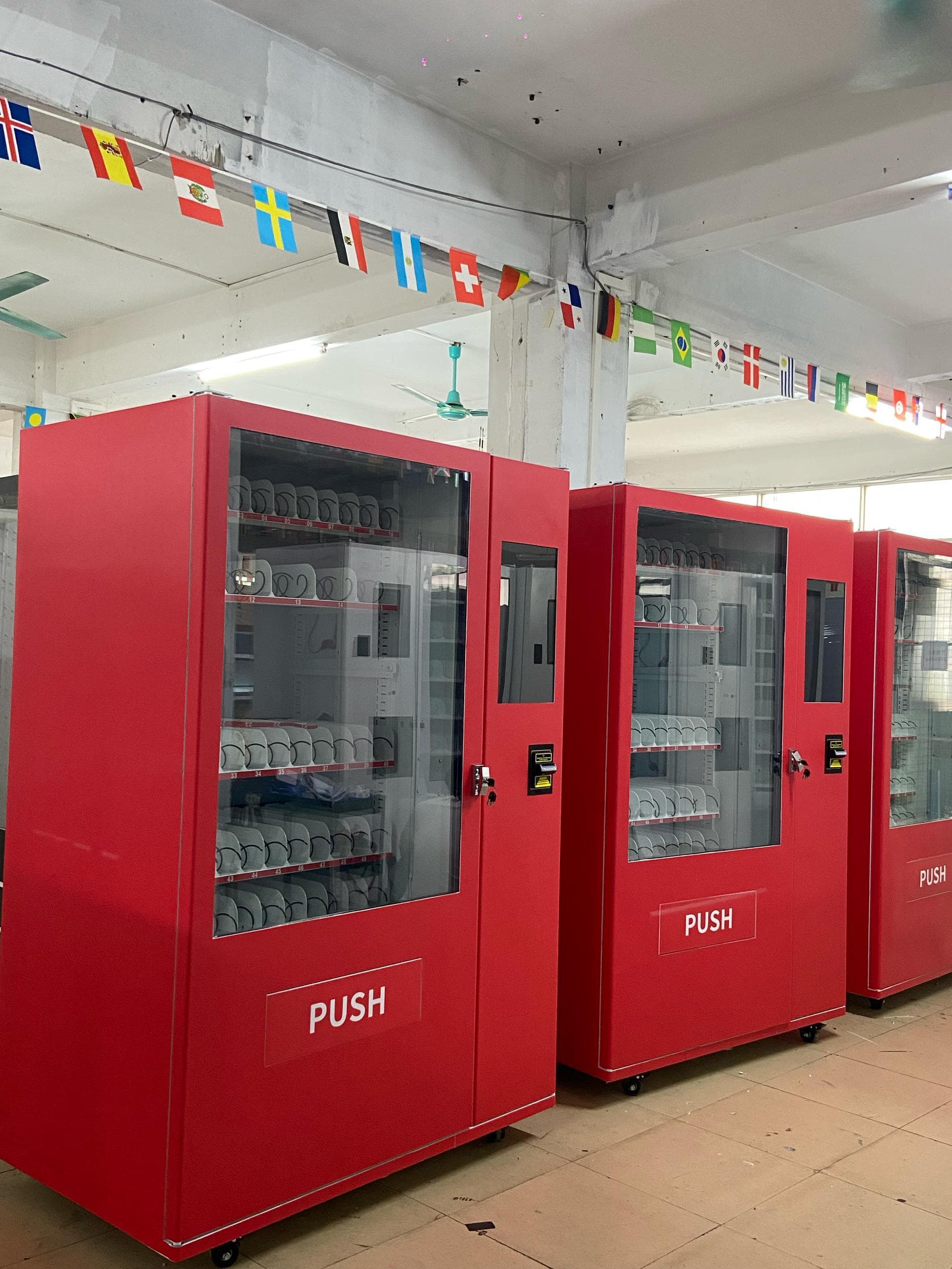 Fila de máquinas expendedoras rojas terminadas en la planta de producción