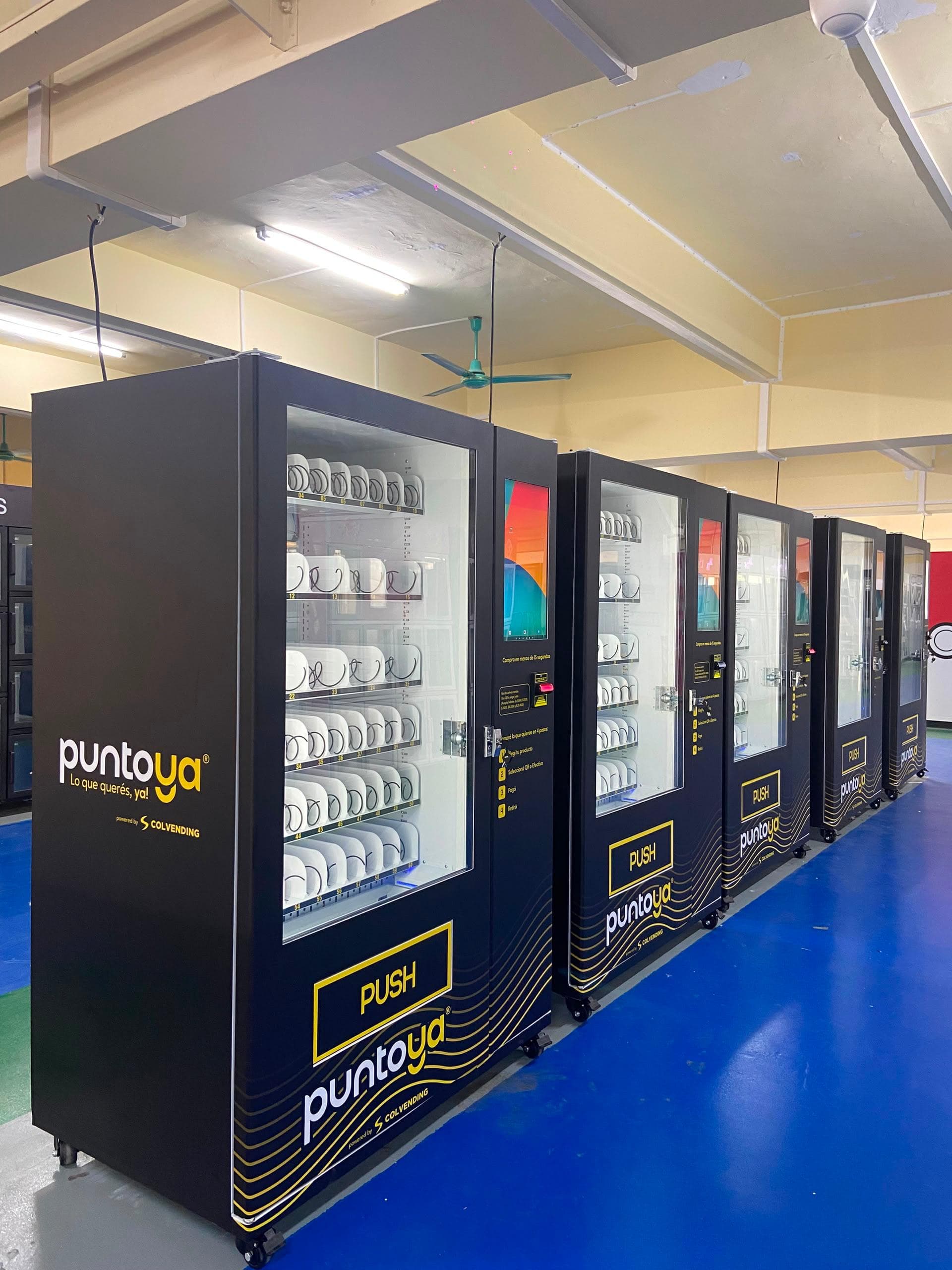 Fila de máquinas expendedoras con la marca Punto Ya en la línea de producción